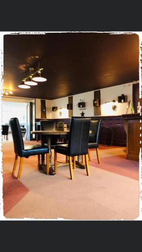 a dining room with black chairs and a table at Hôtel le Bretagne et Restaurant Le Papillon in Gorron