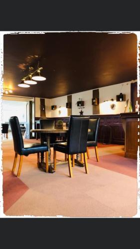una sala da pranzo con sedie nere e tavolo di Hôtel le Bretagne et Restaurant Le Papillon a Gorron