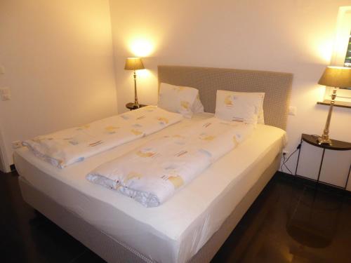 sypialnia z dużym łóżkiem z białą pościelą i poduszkami w obiekcie Rheinblick Résidence w mieście Tägerwilen