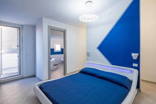 1 Schlafzimmer mit einem blauen Bett und einem Badezimmer in der Unterkunft Bali - BeDreams in Gaeta