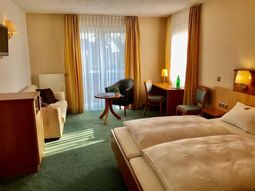 a hotel room with a bed and a chair and a desk at Hotel Haus Deckers in Geldern