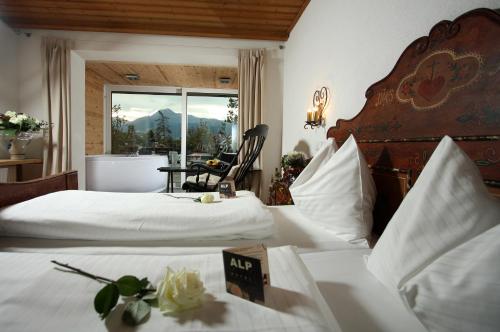 a hotel room with two beds and a chair and a window at Alp Art Hotel Götzens in Innsbruck