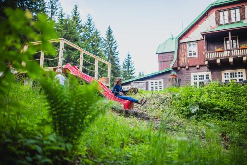 a woman sitting on a slide in a playground at Turnovská chata in Kořenov