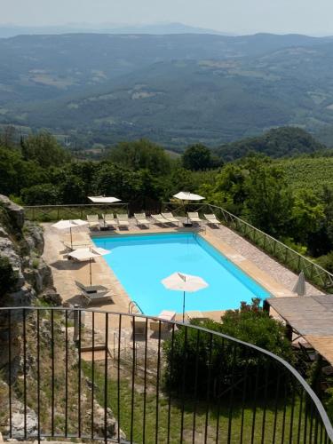 einen Pool mit Stühlen und Sonnenschirmen auf einem Hügel in der Unterkunft Castello di Titignano in Orvieto