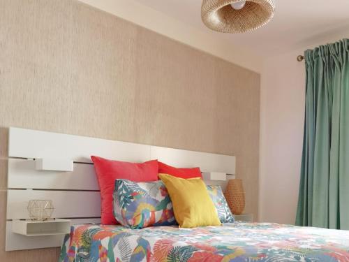 1 dormitorio con 1 cama con almohadas coloridas en Nautilus I: Casa con terraza y vistas al mar en La Caleta