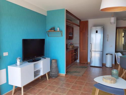 a living room with a television and a blue wall at Nautilus I: Casa con terraza y vistas al mar in La Caleta