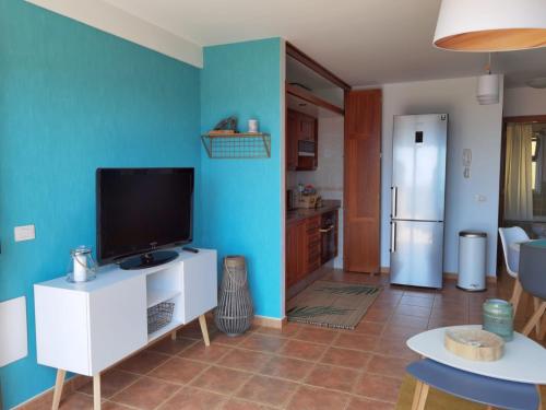 uma sala de estar com televisão e uma parede azul em Nautilus I: Casa con terraza y vistas al mar em La Caleta