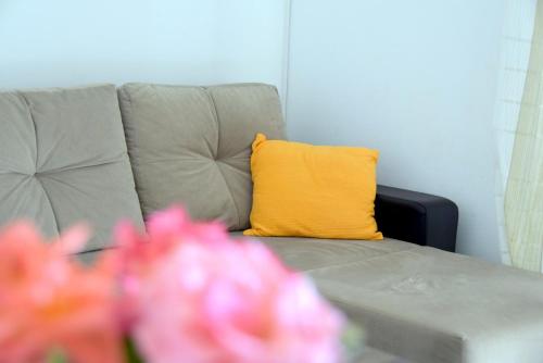 ein gelbes Kissen auf einer grauen Couch mit rosa Blumen in der Unterkunft James Bond Apartments in Rab
