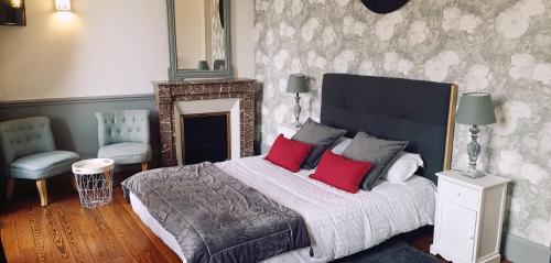 a bedroom with a large bed with two red pillows at Logis Hotel La Tourelle du Beffroi in Bourbon-Lancy