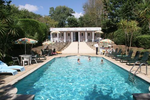 una piscina con gente en ella con una casa en el fondo en The Devoncourt Resort, en Exmouth
