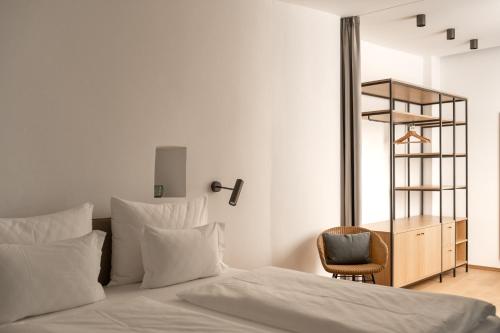 a bed with white sheets and a chair in a room at Kuntino Suites in Merano