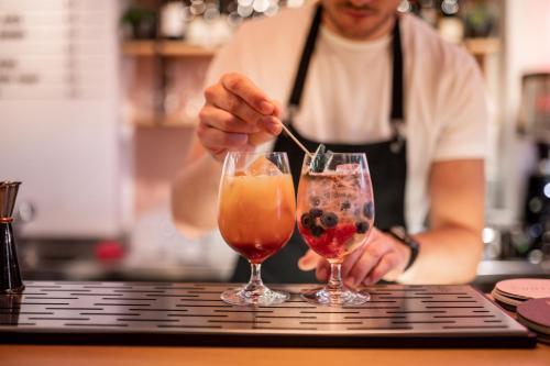 un homme agitant une boisson dans deux verres dans l'établissement Kuntino Suites, à Merano