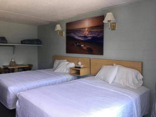 2 bedden in een hotelkamer met witte lakens bij High Seas Motel in Rehoboth Beach