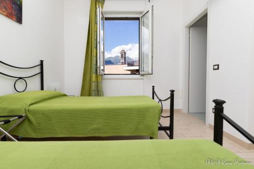 two beds in a room with a window at B&B Casa Fortuna in Lecco