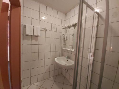 a white tiled bathroom with a sink and a shower at Schwarze Adler in Streitberg