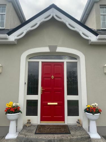 a red door on a house with two vases of flowers at Rockfield Manor B&B, Knock in Knock