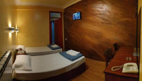 a room with two beds and a table and a phone at ESTRADA Lux in Belgrade