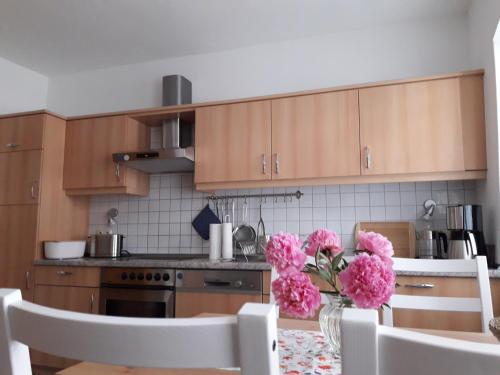 a kitchen with wooden cabinets and pink flowers on a table at Ferienwohnung Kommunikation 5 in Brandenburg an der Havel