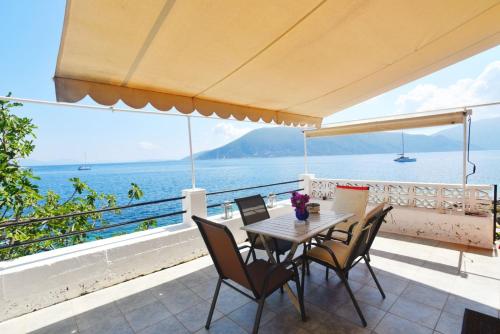einen Tisch und Stühle auf einem Balkon mit Meerblick in der Unterkunft Efi's Cottage by the sea in Fiskardo