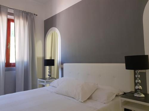 a bedroom with a white bed with two lamps and a window at Hotel Ristorante Radar in Carrara