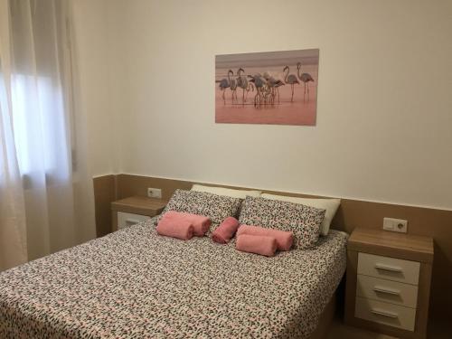 Un dormitorio con una cama con dos almohadas rosas. en Piso centrico cerca del puerto, en Sant Carles de la Ràpita