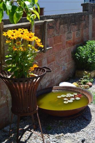a bird bath with a chair and a vase with flowers at Das Nest in Eisenstadt
