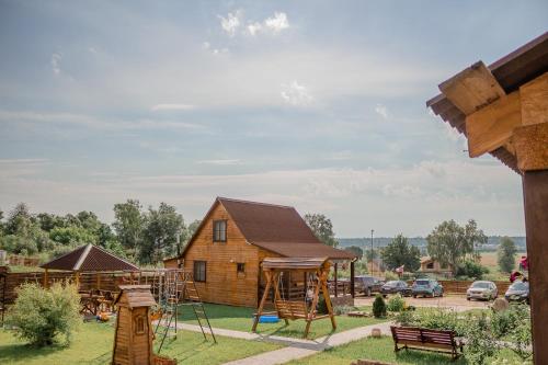 a wooden house with a playground next to a building at Guest House Usadba in Stenino