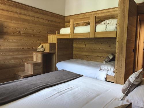 two bunk beds in a room with wooden walls at Hotel Nevada in Bormio