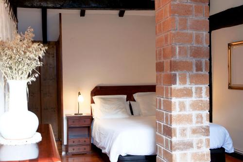 a bedroom with a white bed and a brick wall at Casa Rural Malkornea in Maya del Baztán