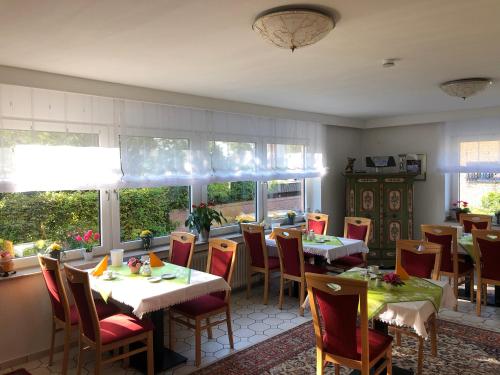 a dining room with tables and chairs and windows at Hotel Haus am Rieth in Nettetal