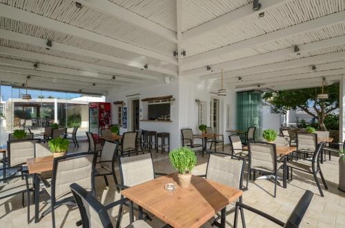 a patio with wooden tables and chairs on a patio at Birikos Hotel & Suites in Agios Prokopios