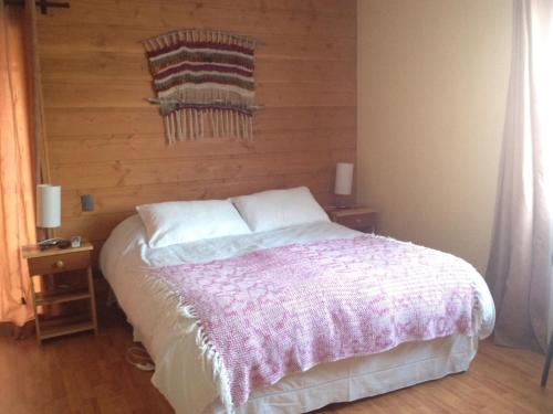 a bedroom with a bed with a wooden wall at Hotel Kernayel in Pucón
