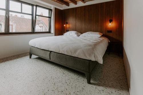 Un dormitorio con una cama grande con una pared de madera. en Jolie Logie, en Nieuwpoort