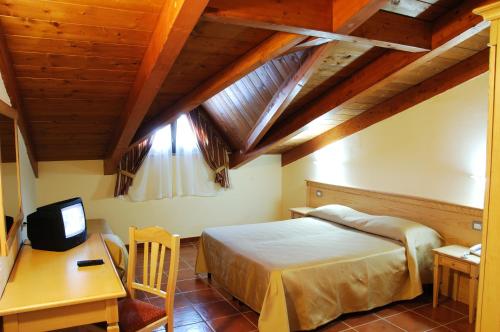 a bedroom with a bed and a desk and a television at Corte dei Greci Resort & Spa in Cariati