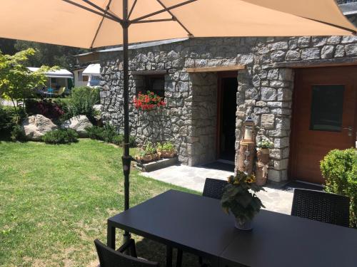 I Larici Camping Lodge في أوسانا: طاولة مع مظلة في الفناء