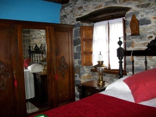 a bedroom with a bed and a stone wall at Casa de Aldea Rural Los Glayus in Luarca