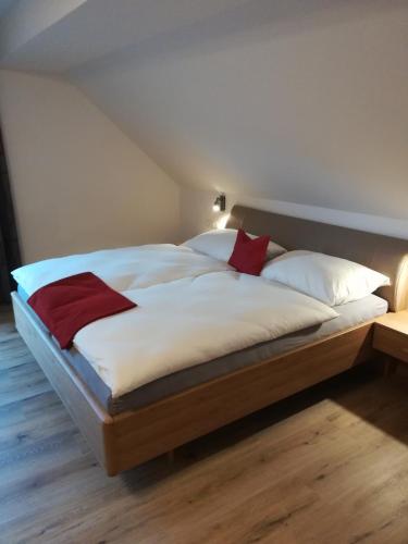 a large bed with white sheets and red pillows at Haus Garz in Weissensee