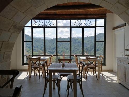 een eetkamer met tafels en stoelen en een groot raam bij La Casa della Filanda in Belmonte Calabro