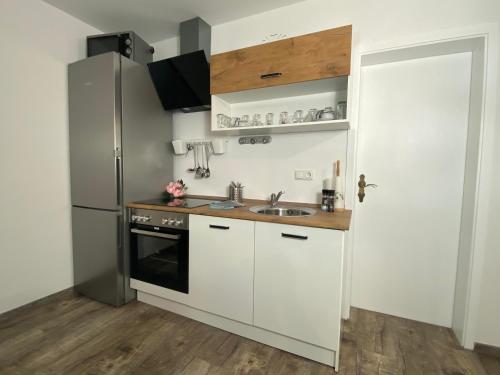 uma cozinha com armários brancos e um frigorífico de aço inoxidável em FeWo Rehblick em Schönau am Königssee