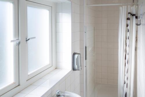 a bathroom with a shower and a toilet and a window at Park Villa Boutique Hostel in London