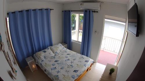 1 dormitorio con 1 cama con cortinas azules y ventana en Marmows Place en San Andrés