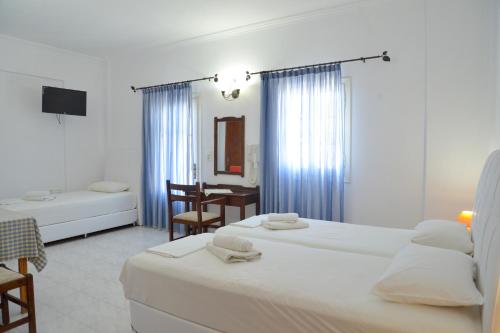 a hotel room with two beds and a desk at Hotel Apartments Giannis in Adamas