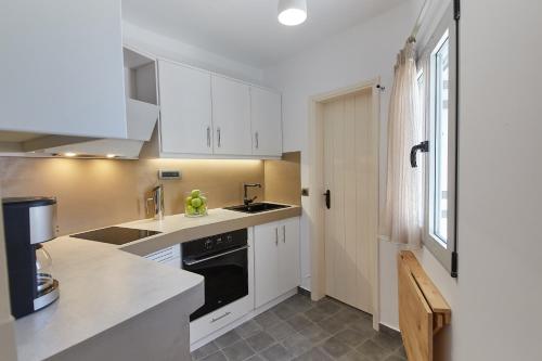 a kitchen with white cabinets and a black dishwasher at Euphoria House in Poros