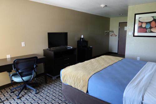 a hotel room with a bed and a desk and a computer at West Worth Inn & Suites White Settlement in White Settlement