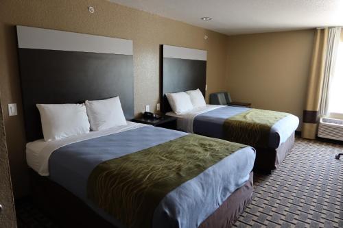 a hotel room with two beds and a window at West Worth Inn & Suites White Settlement in White Settlement