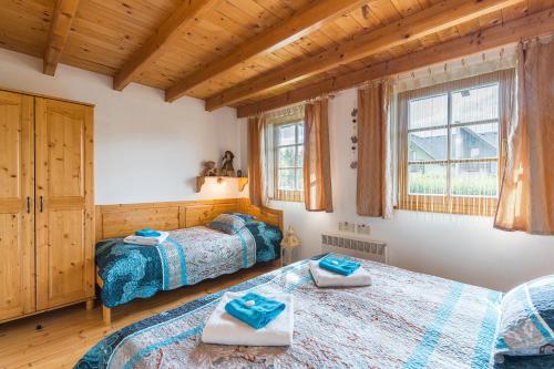 2 Betten in einem Schlafzimmer mit Holzdecken und Fenstern in der Unterkunft Tatralandia Chatky in Liptovský Mikuláš