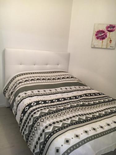 a bed in a white room with a black and white blanket at Vacances à la plage Cabourg F2 in Cabourg