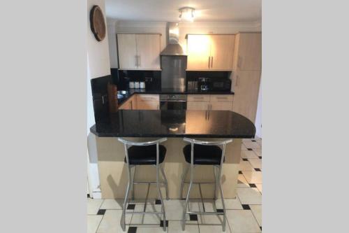 a kitchen with a black counter top and bar stools at A Home Away from Home in Ipswich