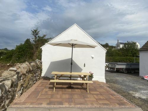 a picnic table with an umbrella in front of a building at Toddys Cottage & Stables in Cavan