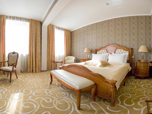 エカテリンブルクにあるグランド ホール ホテルの大きなベッドと椅子が備わるホテルルームです。